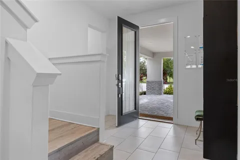 Bright estate foyer with staircase and front entrance